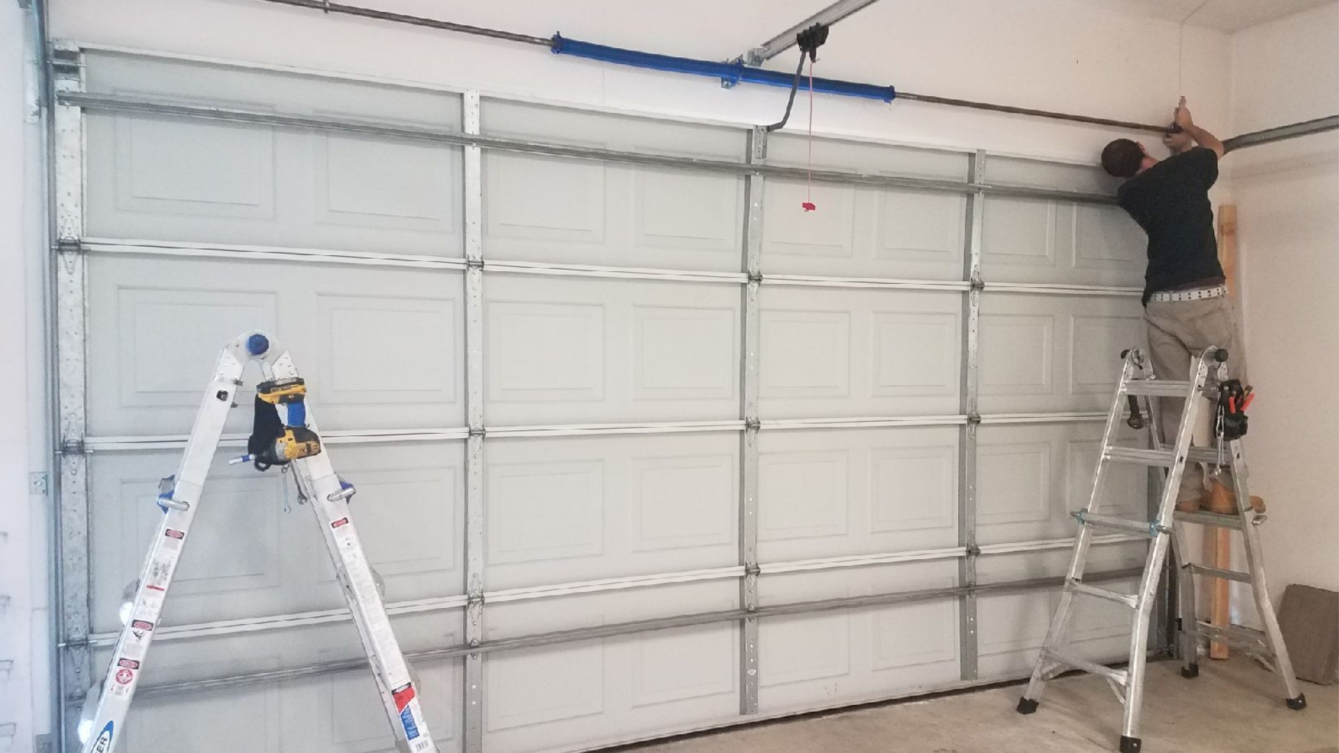 A garage door technician installing a residential garage door