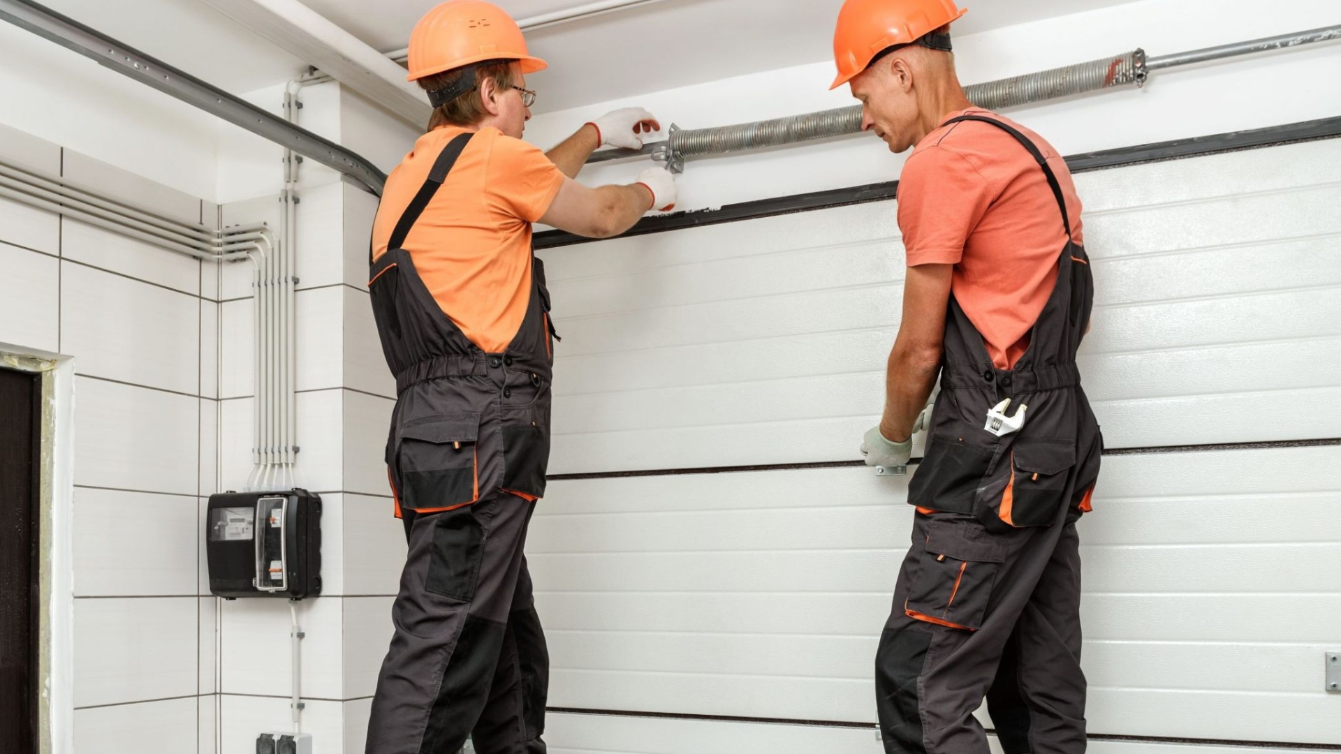 Two men adjusting the garage door spring during a tune-up.