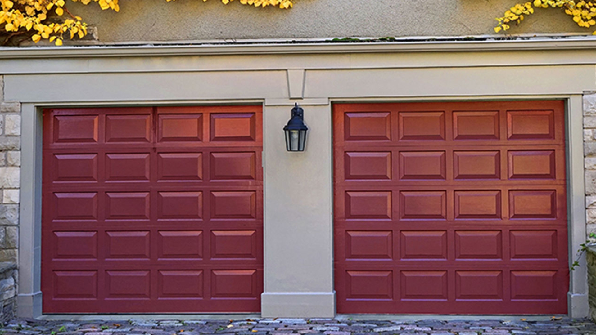 Two-car garage doors painted in red add a vibrant look to a stone exterior home.