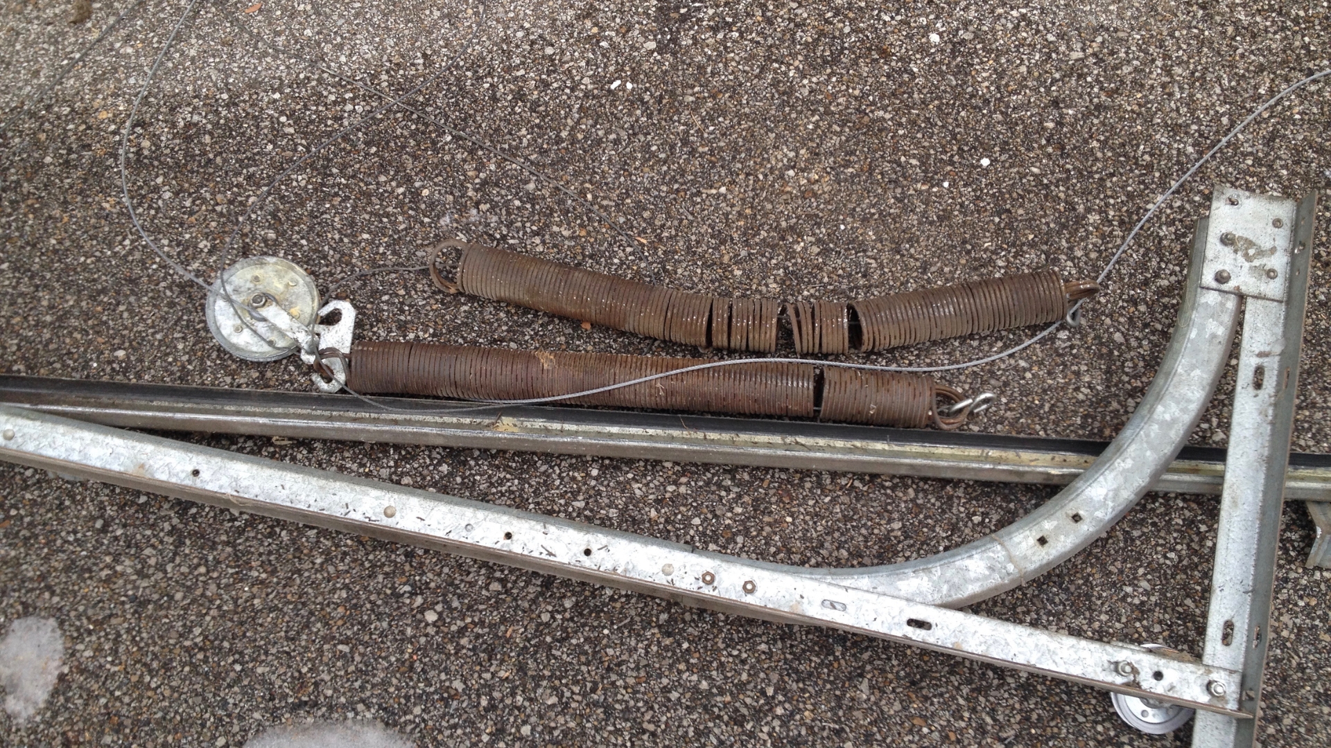 Rusty broken springs and a detached cable, a common cause of a slow garage door.