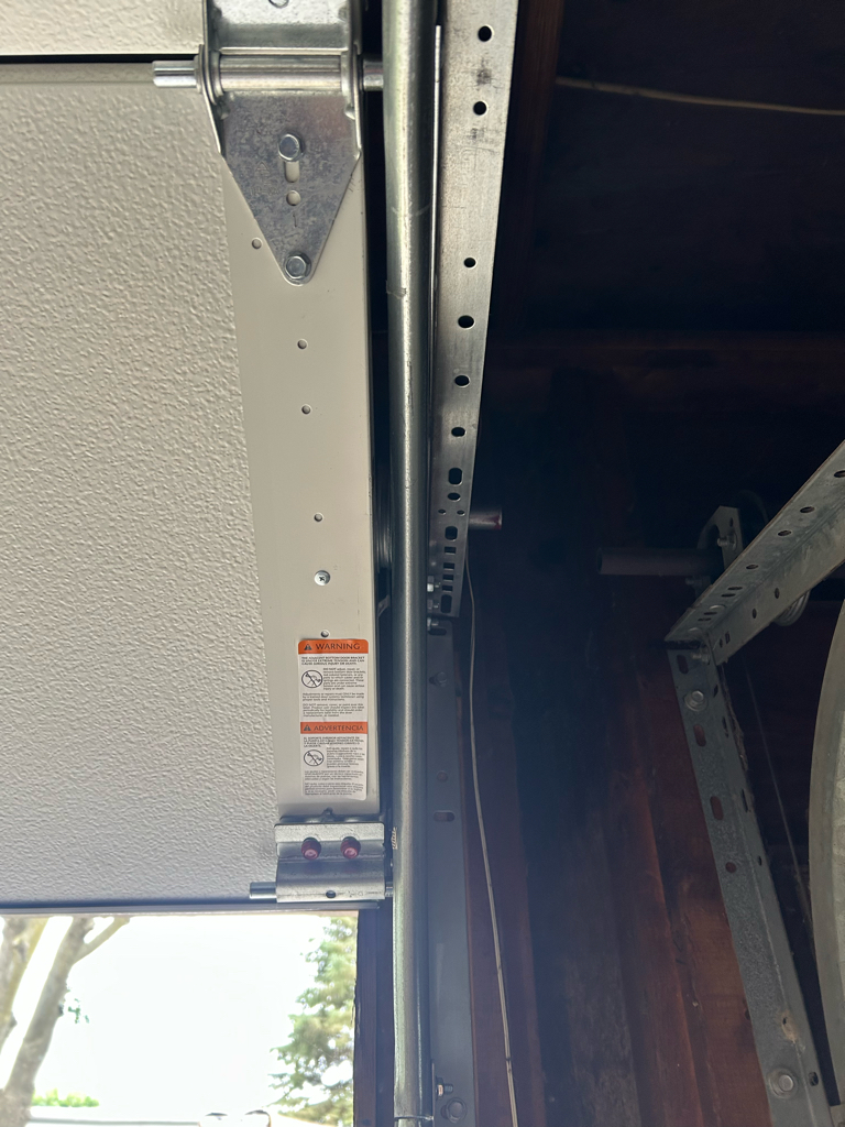 Garage door roller repair showing the vertical track and roller assembly on a residential garage door