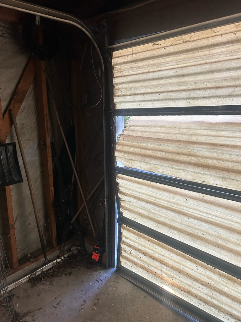 Garage door panel repair showing damaged garage door panels with cracks and large gaps near the side track.