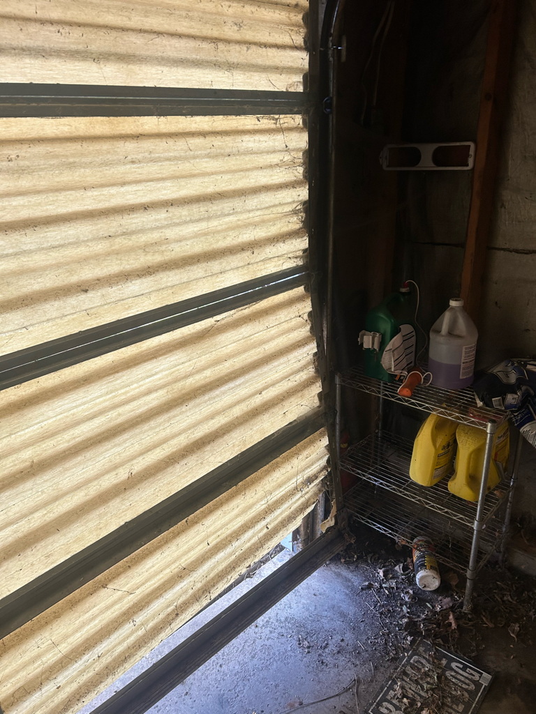 Garage door panel repair showing a damaged lower garage door panel with visible impact damage near the track.