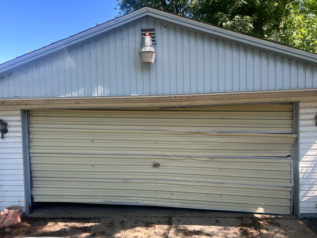 Garage door panel repair showing a severely bent residential garage door with multiple damaged panels.