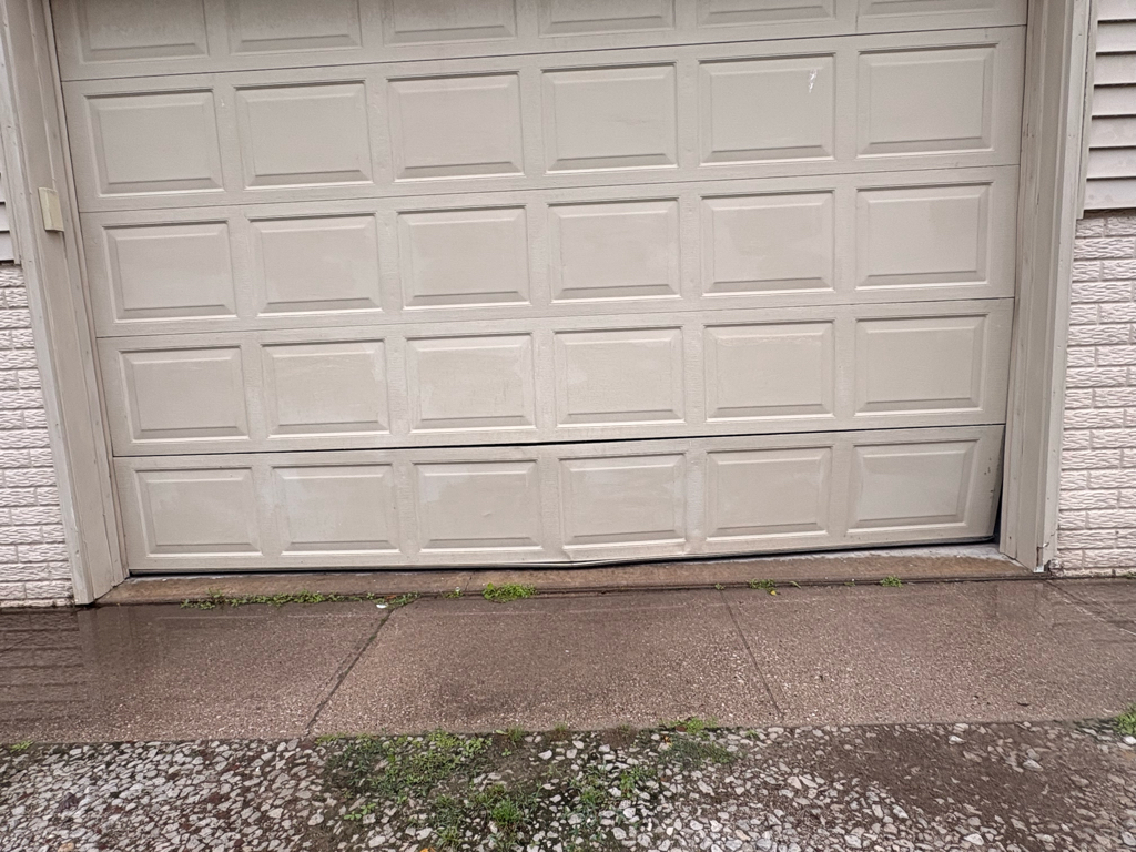 Garage door panel repair showing damaged lower panels on a residential garage door before repair.