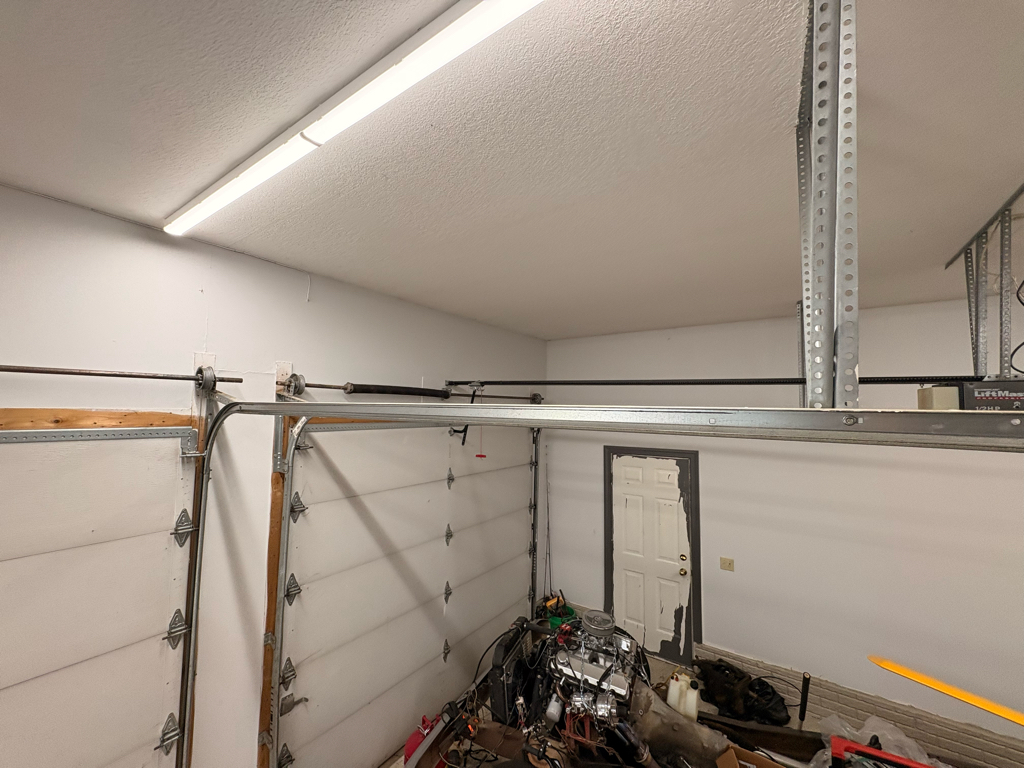 Garage door roller repair showing the upper track, rollers, and torsion spring system inside a residential garage before service.