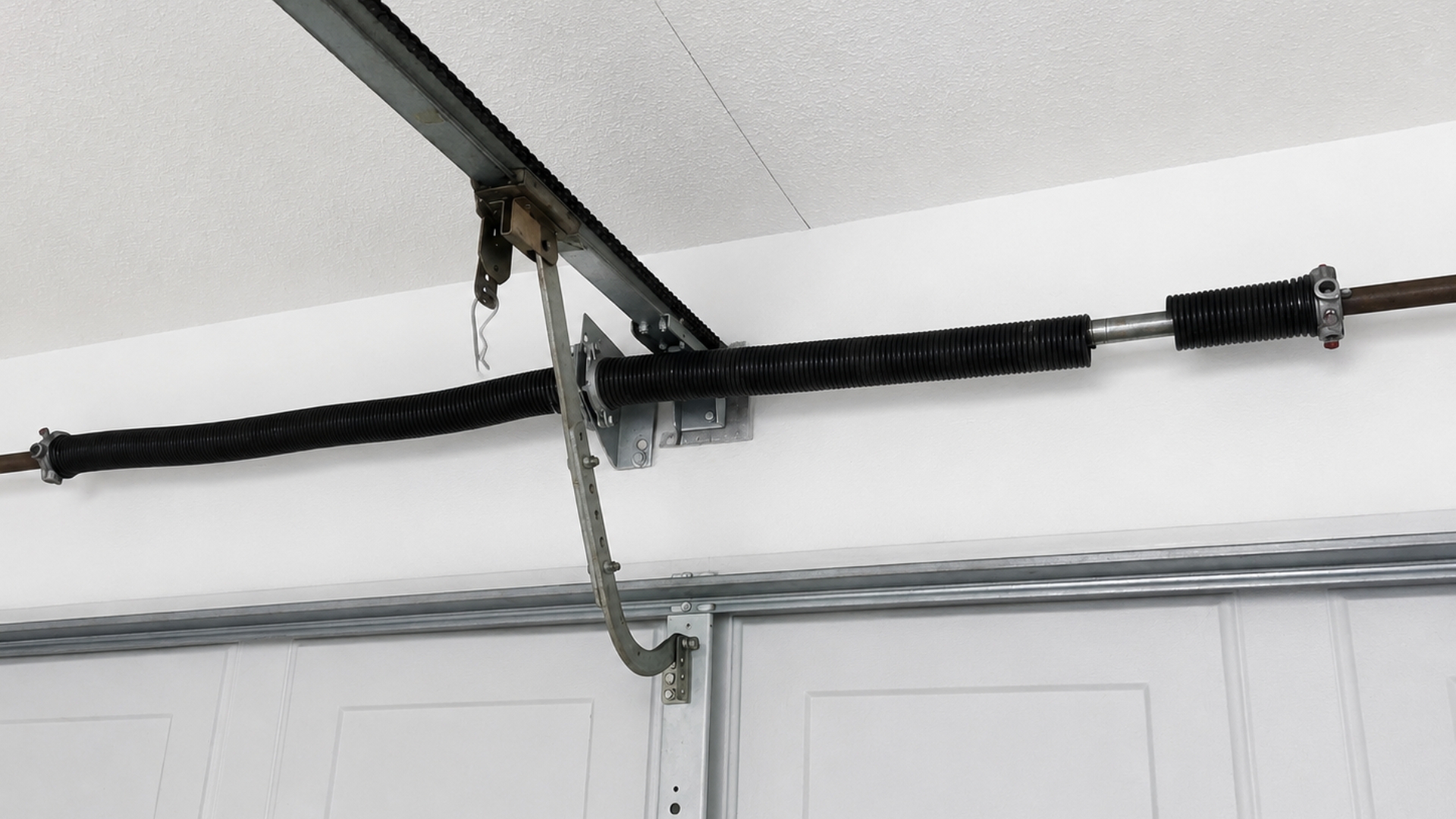 esidential garage door torsion spring system above a sectional door showing the components checked during a garage door repair inspection.