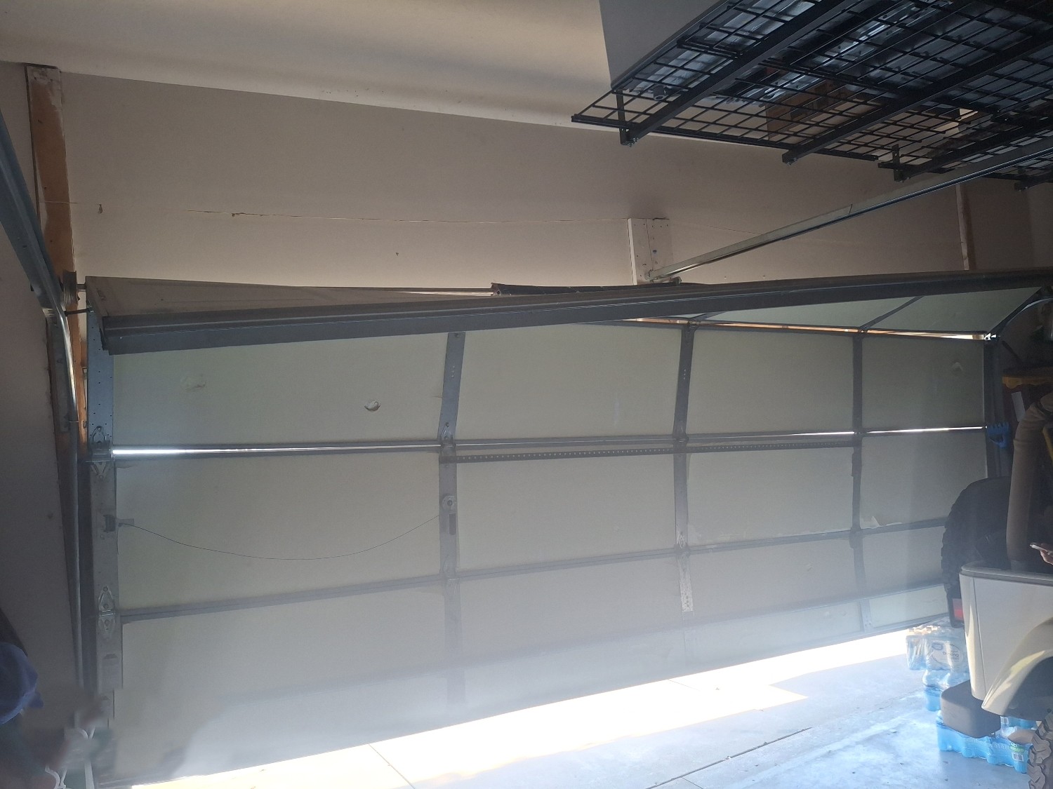 Garage door panel repair showing damaged lower panels on a residential garage door before repair.