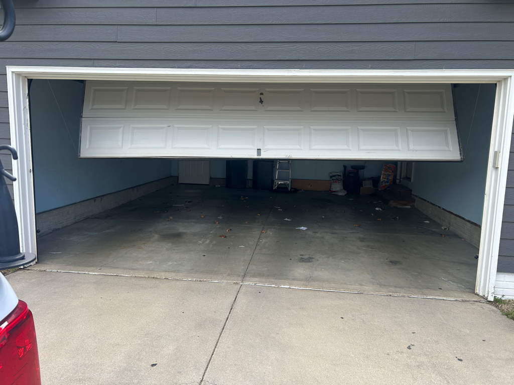 Garage door off-track repair showing a misaligned door inside a garage